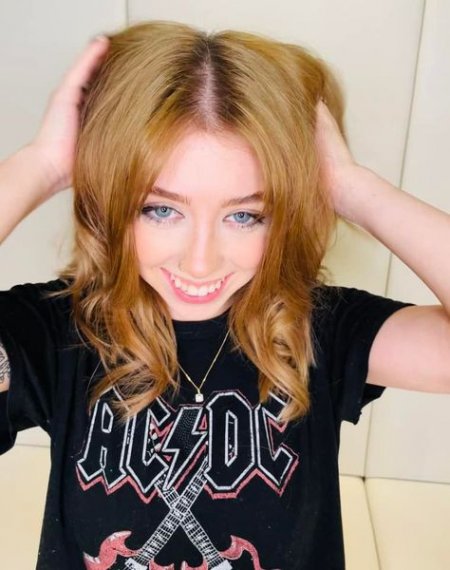 Girl in black acdc tshirt with copper hair cut into long layers