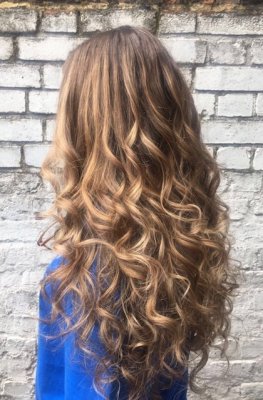 Natural curly hair has been given texture by giving it a natural sunkissed balayage by Leyla at the klinik hairdressing London.
