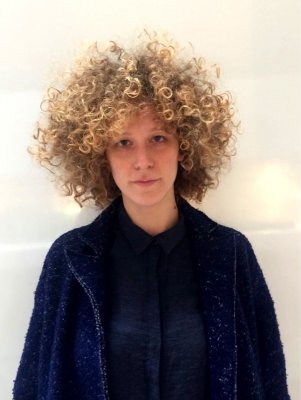 Medium blond hair being cut into a halo shape with large unconected messy curls throughout the hair by Mark at the klinik hairdressing London